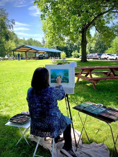 Artist painting canvas on easel at Nature in the Arts event