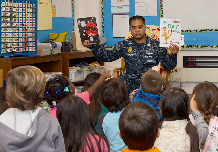 A US Navy sailor holds to Dr. Seuss books up to show school children